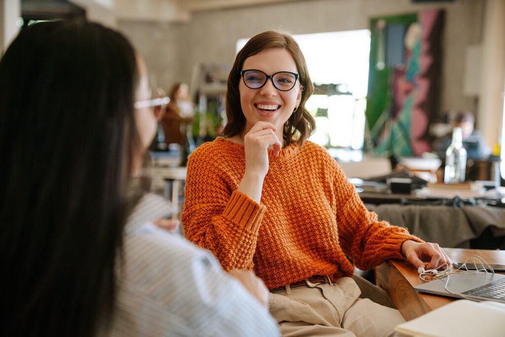 Woman smiling at another woman at a desk